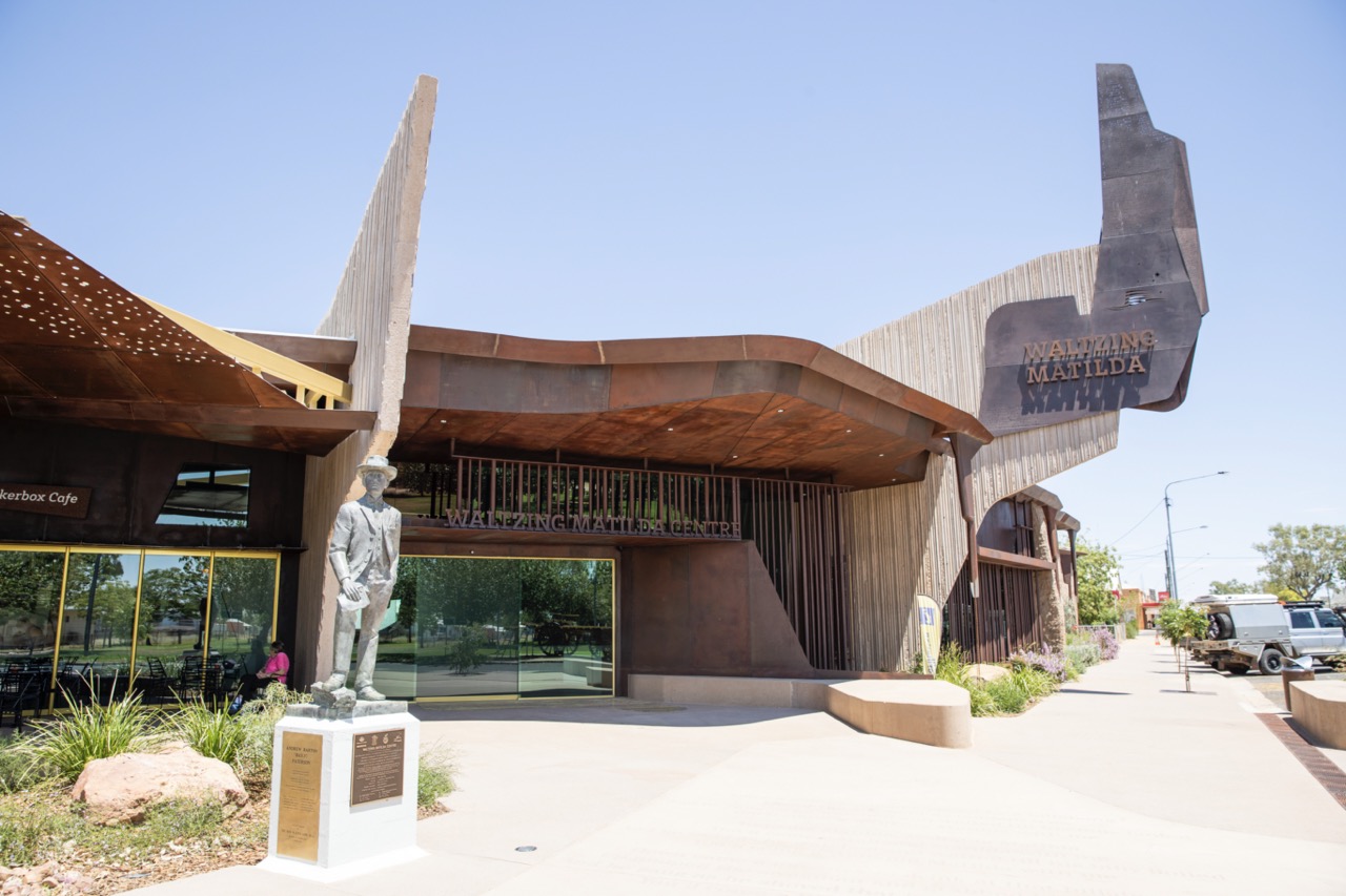 Museum entrance with a modern design and a statue of a soldier in the foreground.