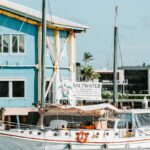 A white sailboat named Saltwater is docked near a blue building, with a sign on the boat advertising eco tours.