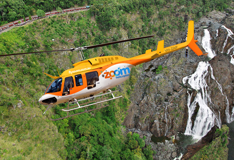 A yellow and white Zoom helicopter flies over a lush green landscape with a waterfall in the background.